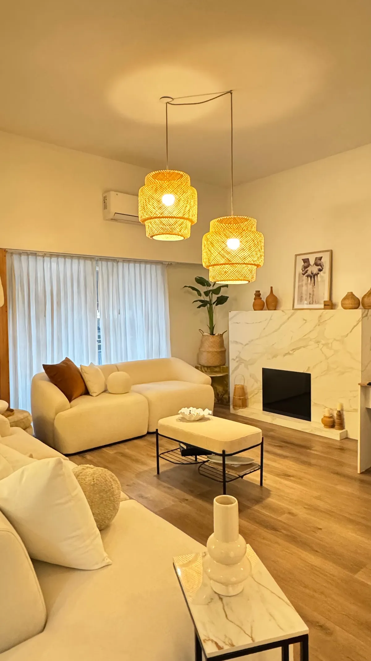 Living de showroom con sofá blanco modular y lámparas de mimbre