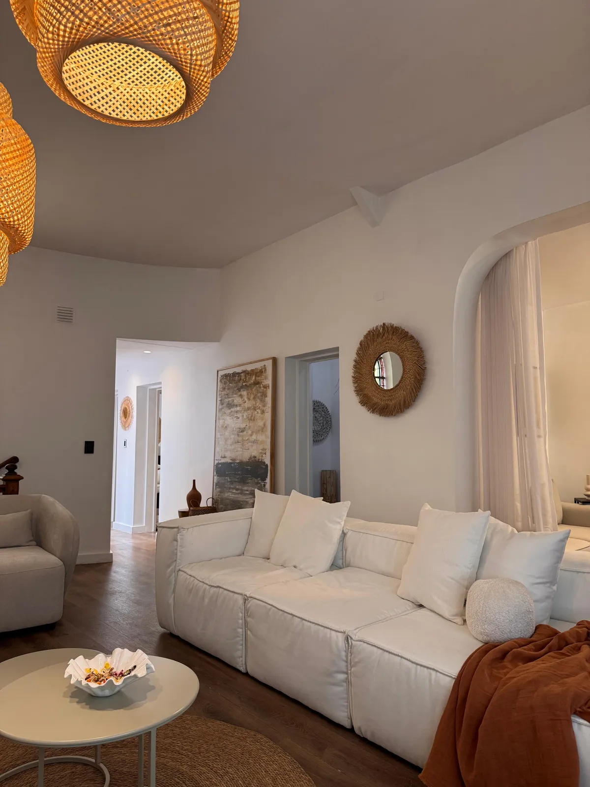 Sofá blanco con cuadro decorativo y espejo de mimbre en el showroom