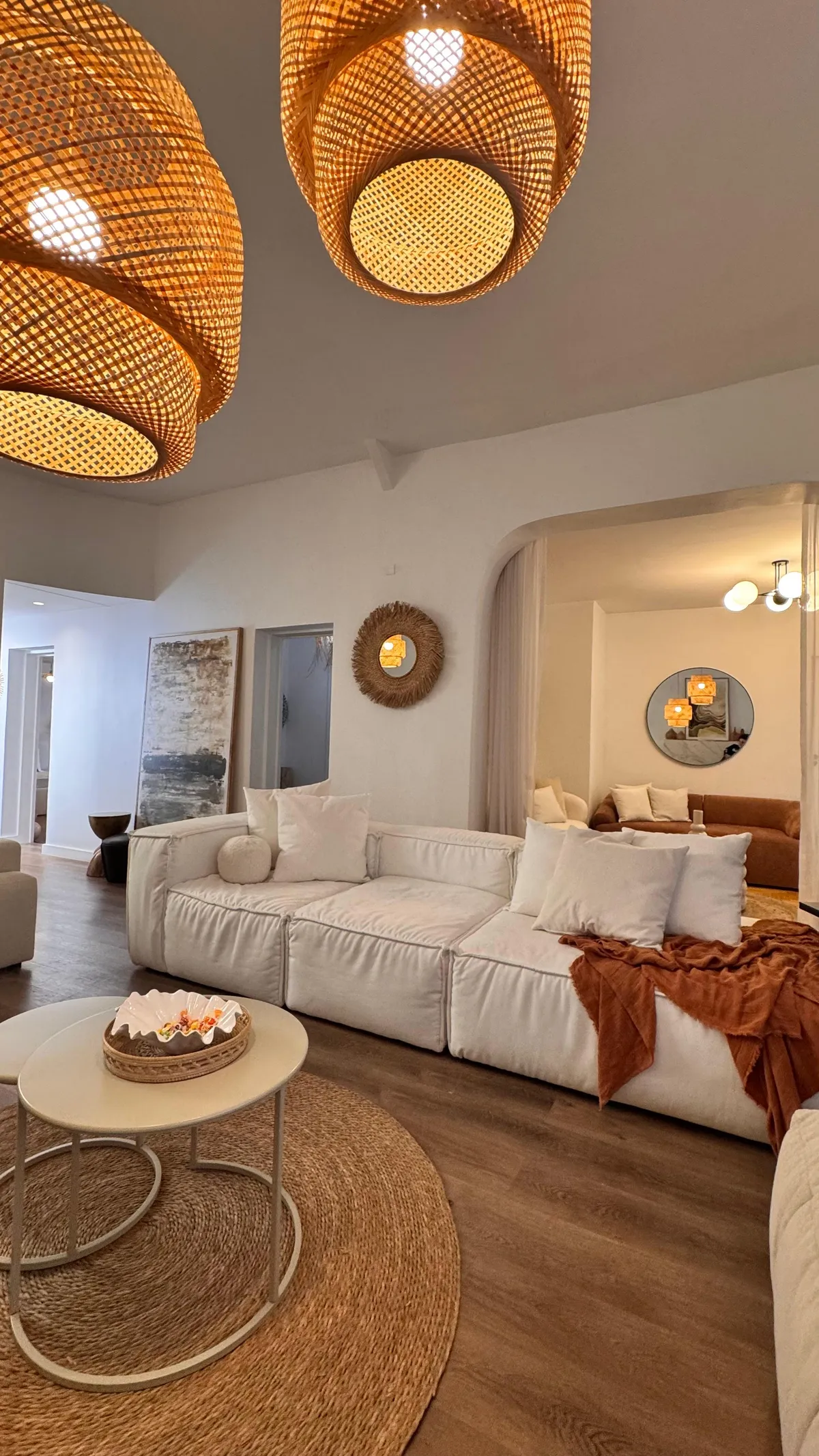 Sofá blanco con almohadones y manta naranja sobre alfombra de yute